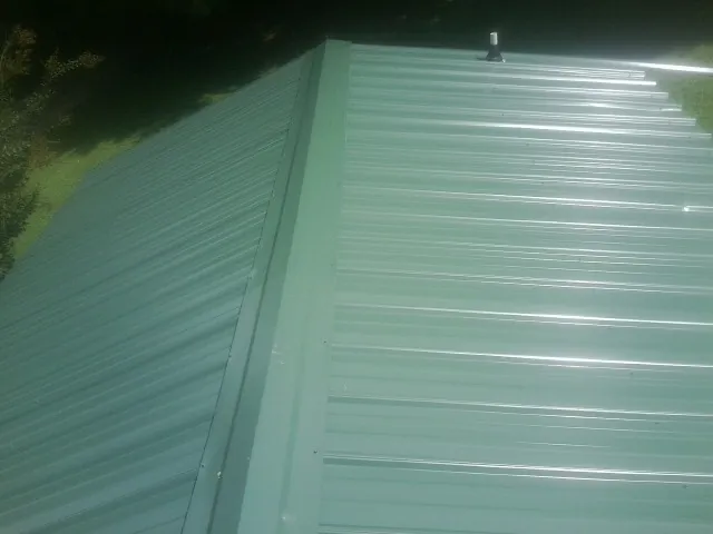 New green metal panels meeting at the ridge of a roof in Harrisville