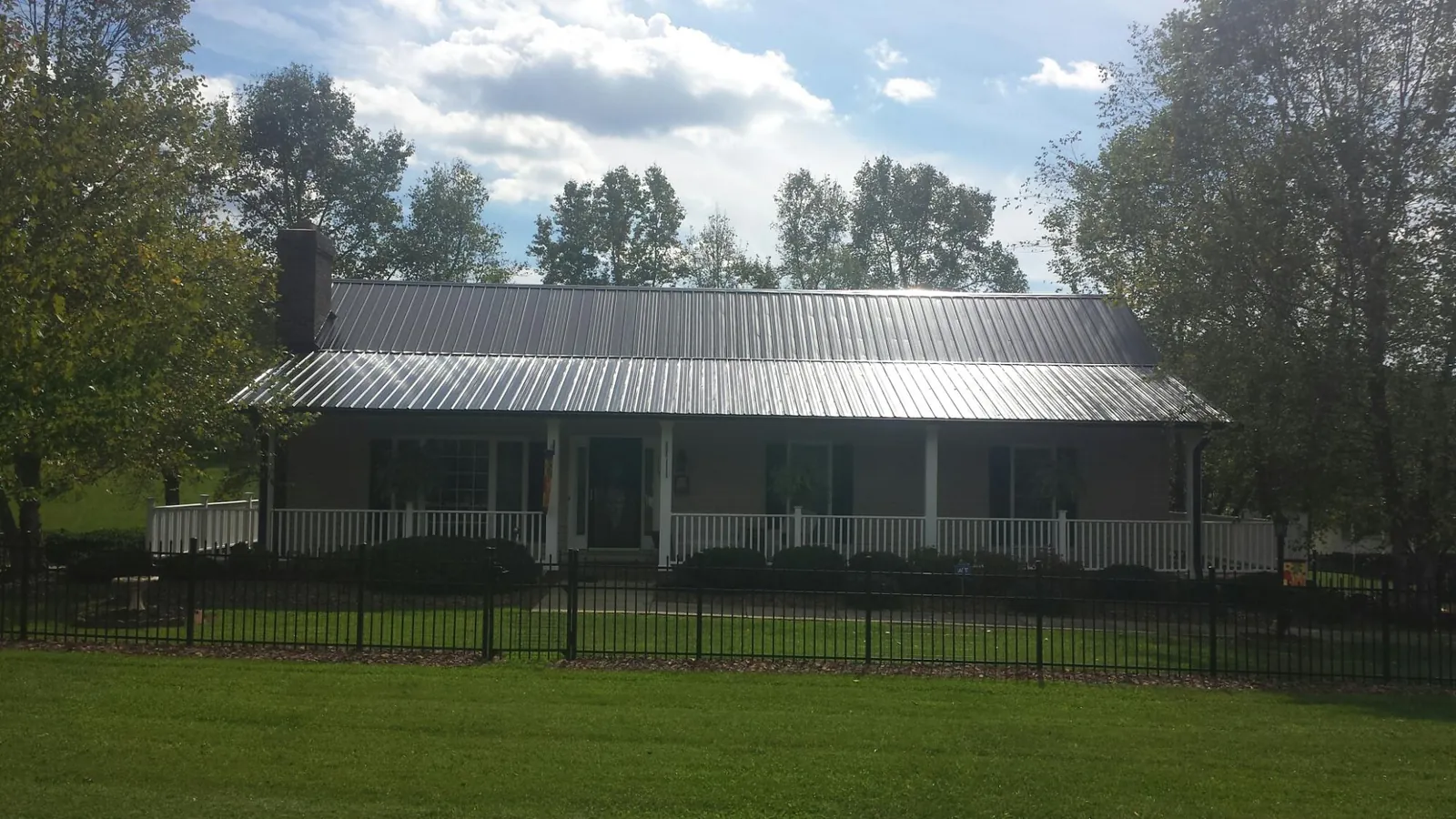 Gray metal roof on a brick ranch with a full width front porch — Gutter Guard Installation work by our crew in Harrisville